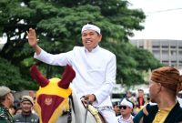 Gubernur Jawa Barat (Jabar) Dedi Mulyadi (KDM) melambaikan tangan kepada warga saat menaiki kuda dalam rangka kirab budaya untuk memperingati Hari Jadi Jabar ke-80, Selasa (19/8/2025). Kirab budaya bergerak mulai dari Gedung Merdeka hingga finis di Gedung Sate, Jalan Diponegoro, Kota Bandung.(DOK. Pemprov Jawa Barat)
