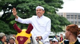 Gubernur Jawa Barat (Jabar) Dedi Mulyadi (KDM) melambaikan tangan kepada warga saat menaiki kuda dalam rangka kirab budaya untuk memperingati Hari Jadi Jabar ke-80, Selasa (19/8/2025). Kirab budaya bergerak mulai dari Gedung Merdeka hingga finis di Gedung Sate, Jalan Diponegoro, Kota Bandung.(DOK. Pemprov Jawa Barat)

