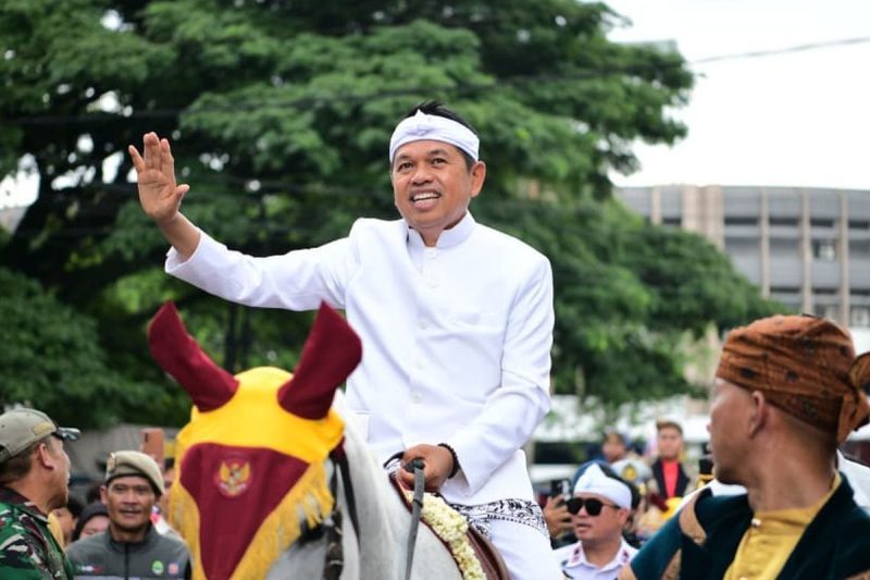 Gubernur Jawa Barat (Jabar) Dedi Mulyadi (KDM) melambaikan tangan kepada warga saat menaiki kuda dalam rangka kirab budaya untuk memperingati Hari Jadi Jabar ke-80, Selasa (19/8/2025). Kirab budaya bergerak mulai dari Gedung Merdeka hingga finis di Gedung Sate, Jalan Diponegoro, Kota Bandung.(DOK. Pemprov Jawa Barat)
